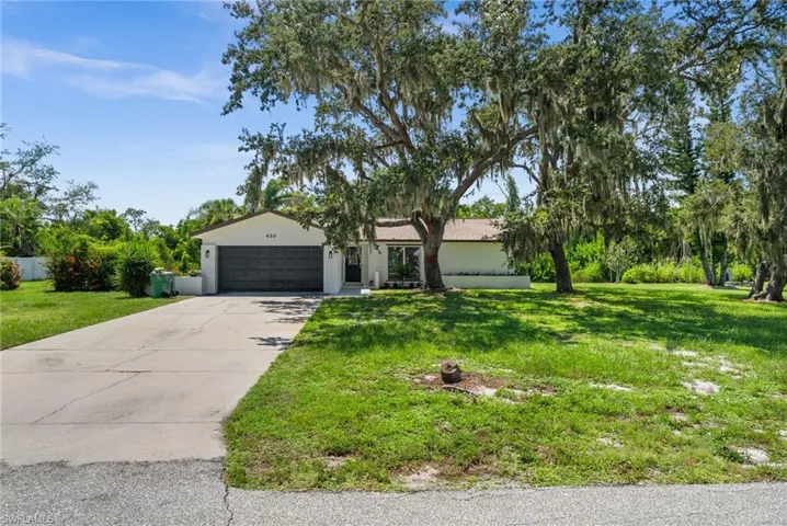 View of front of property featuring an attached garage, stucco siding, a front yard, and driveway