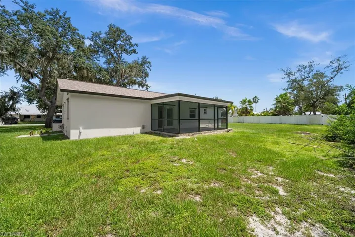 Back of property with a sunroom, stucco siding, and a shingled roof