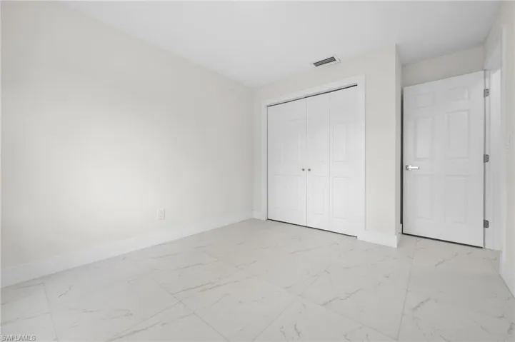 Unfurnished bedroom featuring light marble finish flooring and a closet