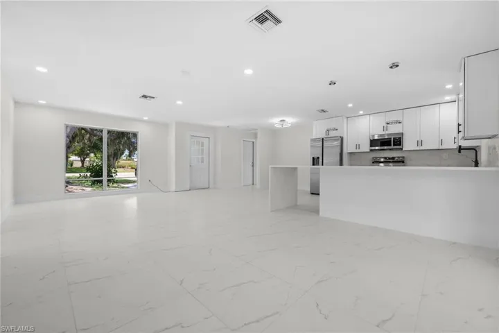 Unfurnished living room featuring light marble finish flooring and recessed lighting