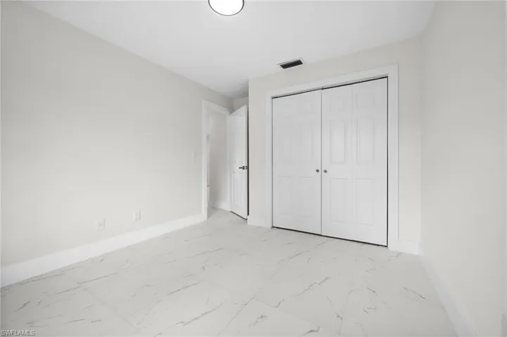 Unfurnished bedroom featuring light marble finish floors and a closet