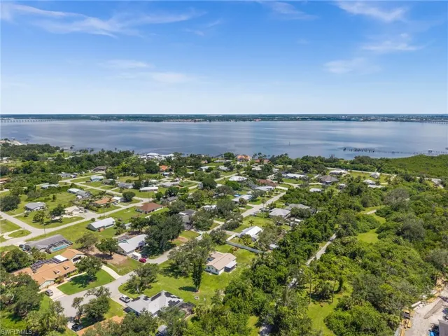 Aerial view of property and surrounding area with a nearby body of water and nearby suburban area