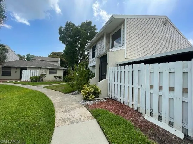 Two-story exterior with light-colored siding and a white privacy fence