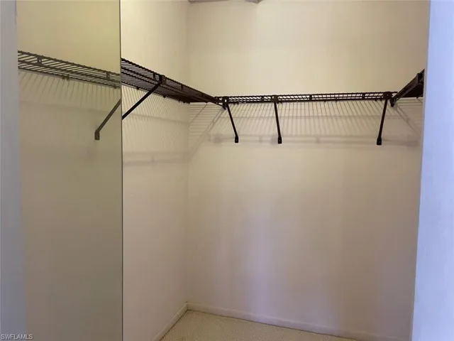 Corner closet featuring a built-in wire shelving system, integrated hanging rods, and light-toned wall finishes