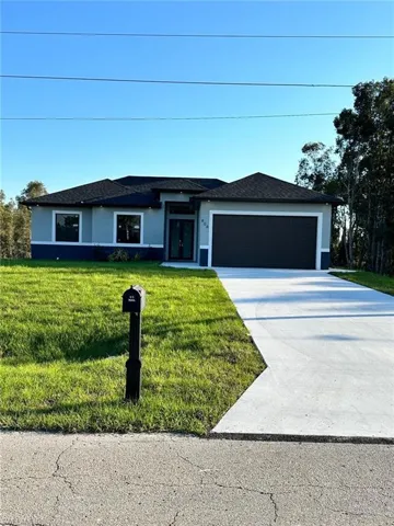 View of front with concrete driveway, a front yard, an attached garage, and stucco siding