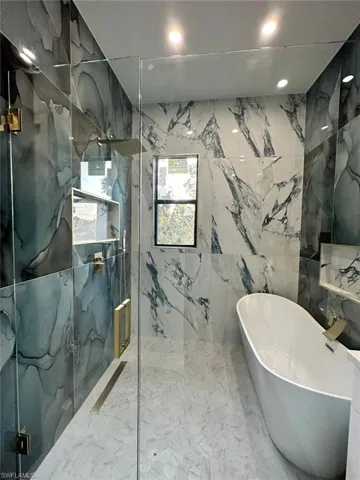 Bathroom featuring a freestanding bath and a marble finish shower