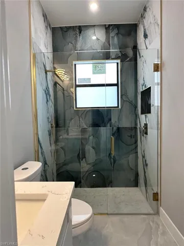 Full bathroom with a marble finish shower, vanity, toilet, and marble finish floor