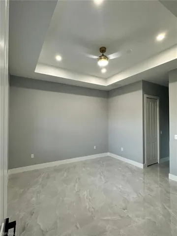 Master bedroom with a tray ceiling and baseboards