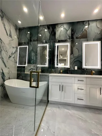 Bathroom with marble finish floor, double vanity, and a freestanding bath