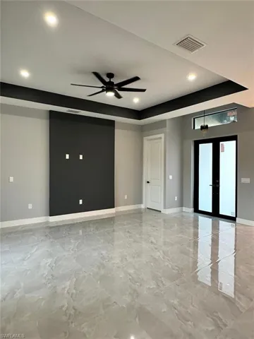 Living room featuring baseboards, marble finish floor, french doors, and a raised ceiling