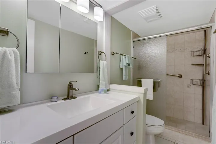Guest bathroom with newer vanity, lighting, plumbing fixtures & custom tiled shower.