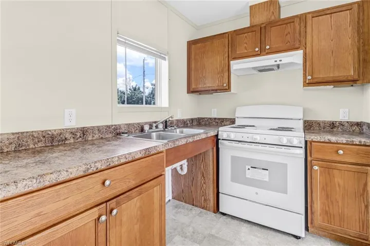 Kitchen featuring sink, light tile floors, and white stove