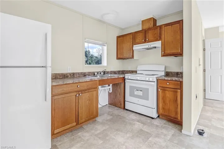 Kitchen featuring white appliances, sink, and light tile floors