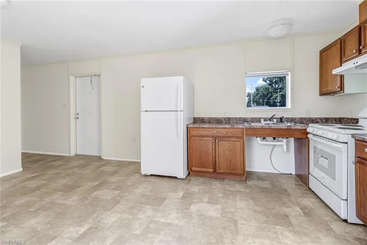 Kitchen with sink, white appliances, and light tile floors