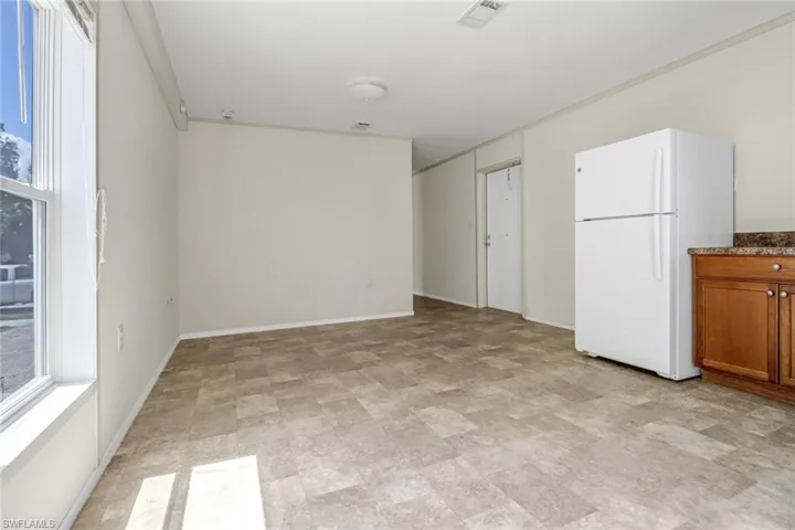 Unfurnished bedroom with a closet, white refrigerator, and light tile floors