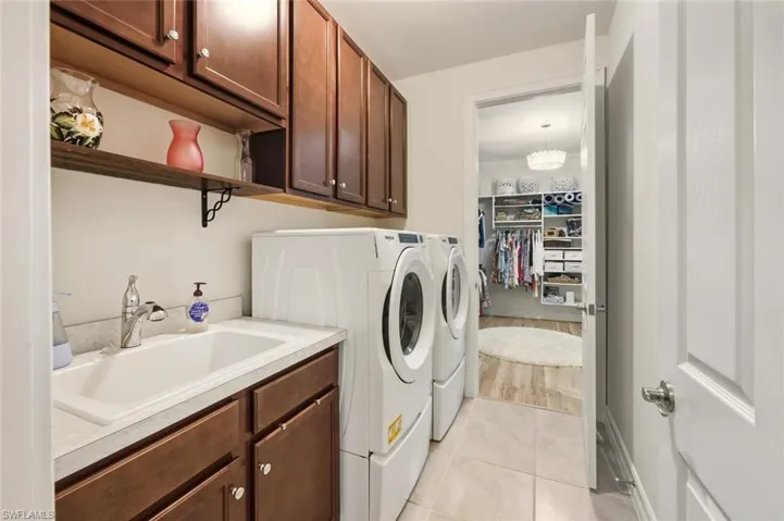 Laundry area featuring cabinet space, washing machine and dryer, and light tile patterned floors