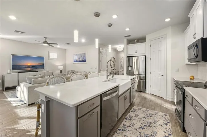 Kitchen with a breakfast bar area, pendant lighting, stainless steel appliances, open floor plan, and wood tiled floors