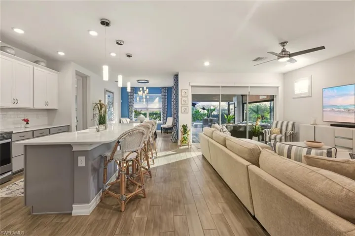 Kitchen with open floor plan, white cabinetry, a kitchen bar, a center island with sink, and backsplash
