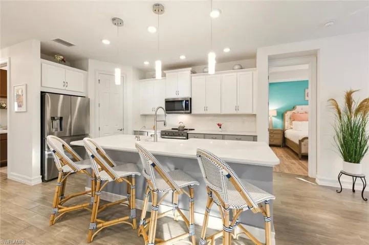Kitchen with appliances with stainless steel finishes, hanging light fixtures, white cabinets, light wood-style flooring, and recessed lighting
