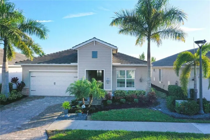 View of front facade with an attached garage, stucco siding, decorative driveway, and a front lawn
