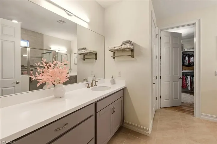 Bathroom featuring vanity, a shower stall, a walk in closet, and light tile patterned flooring