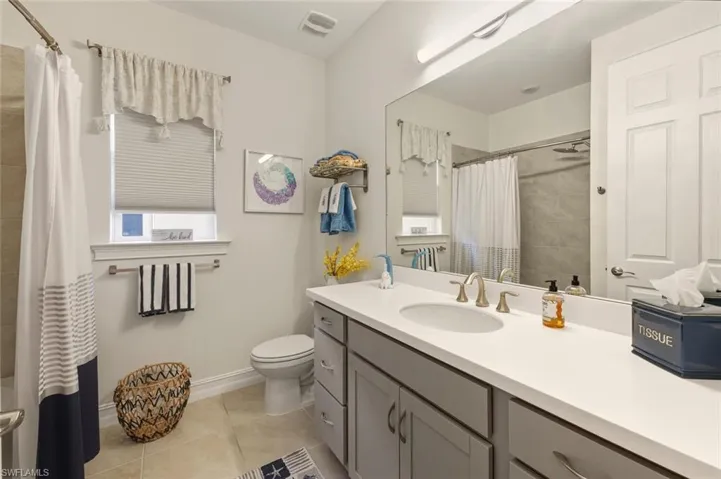 Full bath featuring vanity, light tile patterned floors, and shower / bathtub combination with curtain