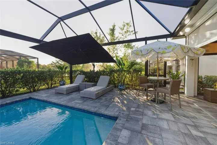 Outdoor pool with glass enclosure, a patio area, a sunroom, and outdoor dining area
