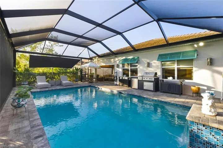 Swimming pool featuring a lanai, a sunroom, exterior kitchen, and a patio