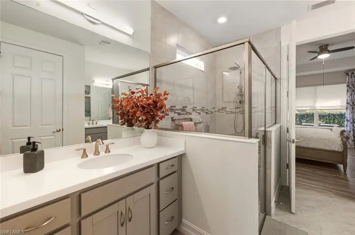 Bathroom with vanity, ensuite bathroom, ceiling fan, a shower stall, and light tile patterned floors