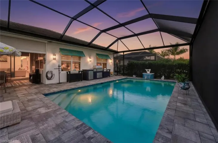 Outdoor pool featuring a lanai, a sunroom, an outdoor kitchen, and a patio area