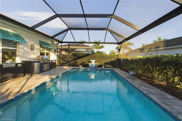 Outdoor pool featuring a lanai, exterior kitchen, a patio area, and a sunroom