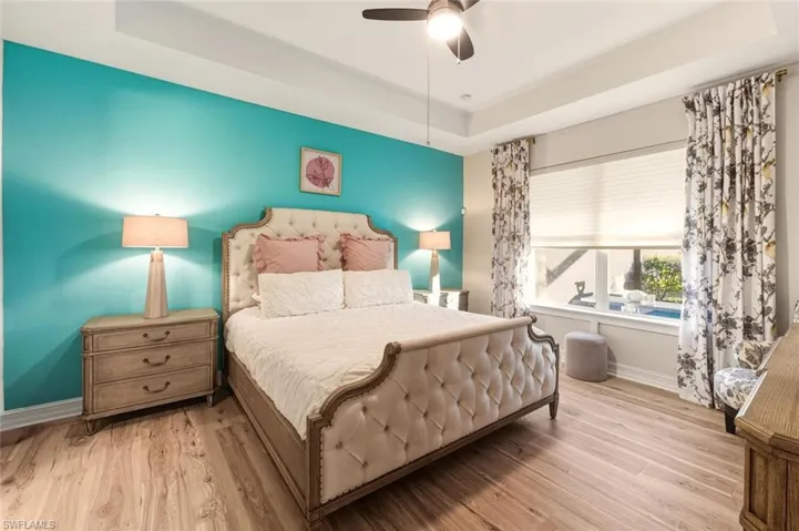 Bedroom with a tray ceiling, wood finished floors, and ceiling fan
