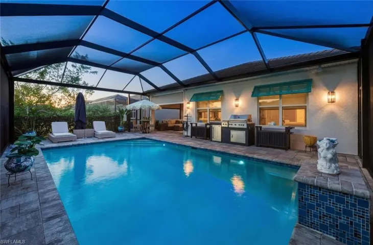 Swimming pool with a lanai, a sunroom, a patio, and exterior kitchen