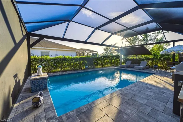 View of swimming pool featuring a lanai, a sunroom, and a patio
