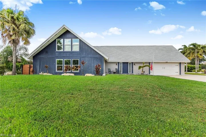 View of front facade with a front yard, driveway, an attached garage, and a shingled roof