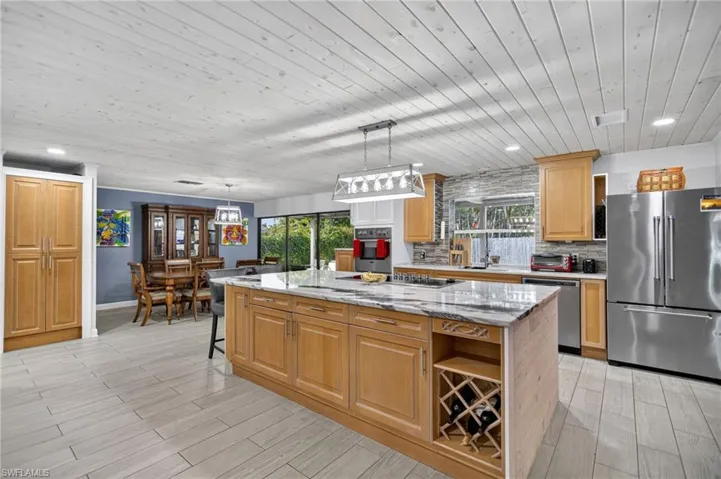 Kitchen featuring stainless steel appliances, wood ceiling, decorative backsplash, wood tiled floors, and light stone countertops