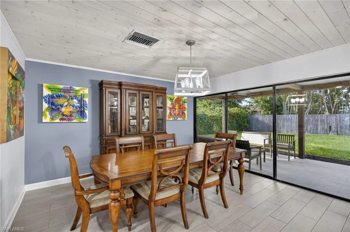 Dining room featuring light wood-type flooring, a chandelier, wooden ceiling, and crown molding