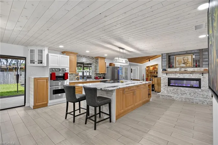 Kitchen featuring wooden ceiling, pendant lighting, a breakfast bar area, a kitchen island, and wood tiled floors