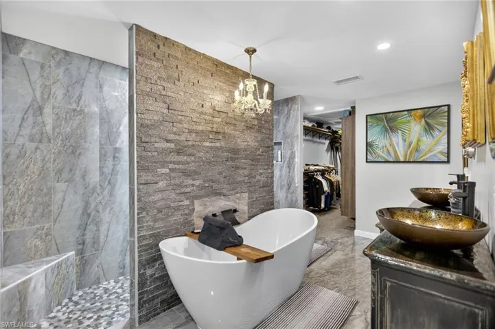 Full bath featuring a spacious closet, a soaking tub, double vanity, walk in shower, and recessed lighting