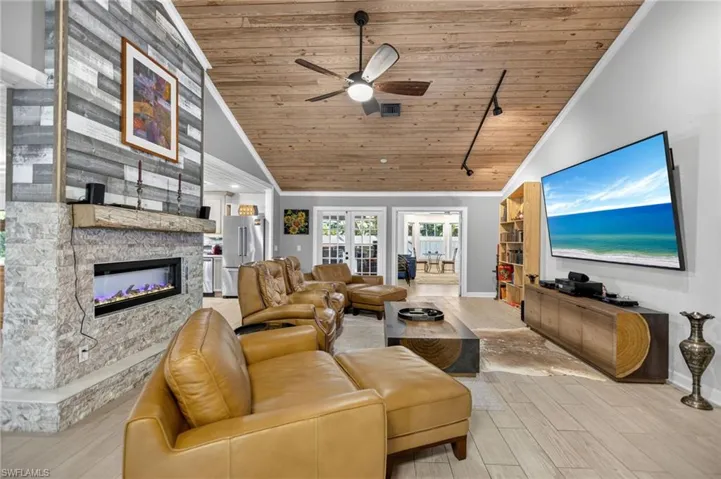Living room featuring track lighting, wooden ceiling, light wood-type flooring, a fireplace, and high vaulted ceiling