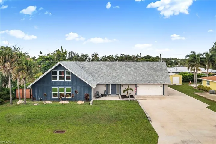 View of front of property with concrete driveway, a front lawn, a porch, and roof with shingles