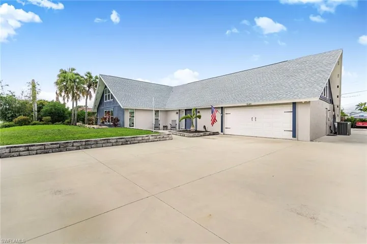 View of front facade featuring driveway, roof with shingles, a front lawn, an attached garage, and stucco siding