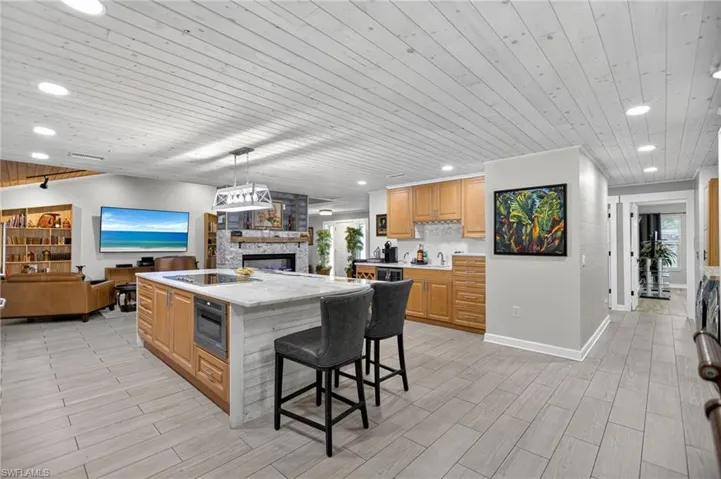 Kitchen featuring wood ceiling, open floor plan, a stone fireplace, decorative light fixtures, and recessed lighting