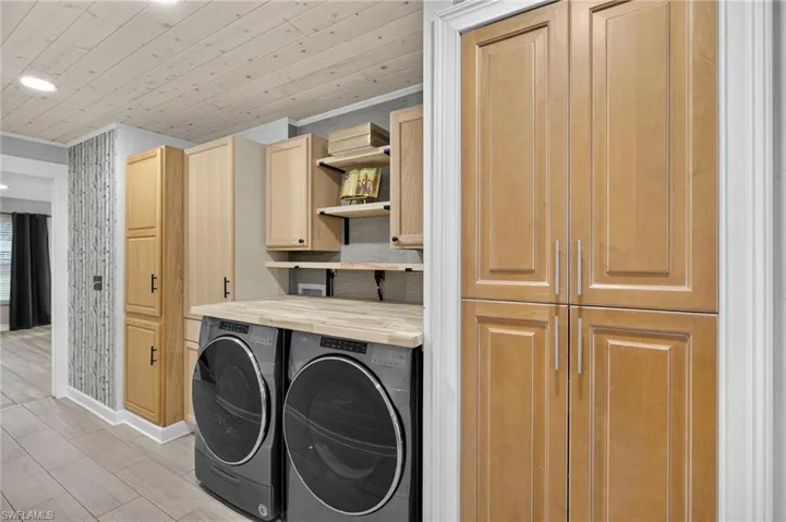 Washroom featuring cabinet space, washing machine and clothes dryer, wood ceiling, wood tiled floors, and recessed lighting