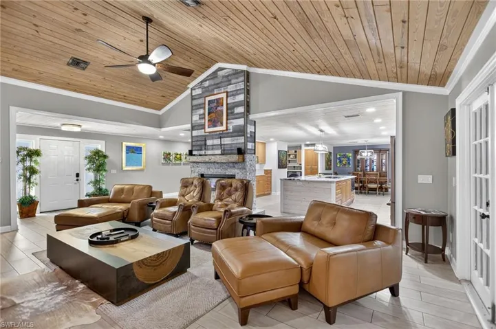 Living room with crown molding, wood ceiling, wood finish floors, high vaulted ceiling, and a ceiling fan