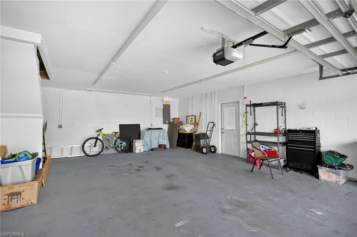 Garage featuring concrete block wall, a garage door opener, and electric panel
