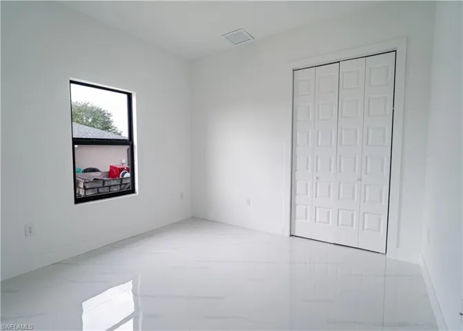 Unfurnished bedroom with light marble finish floors and a closet