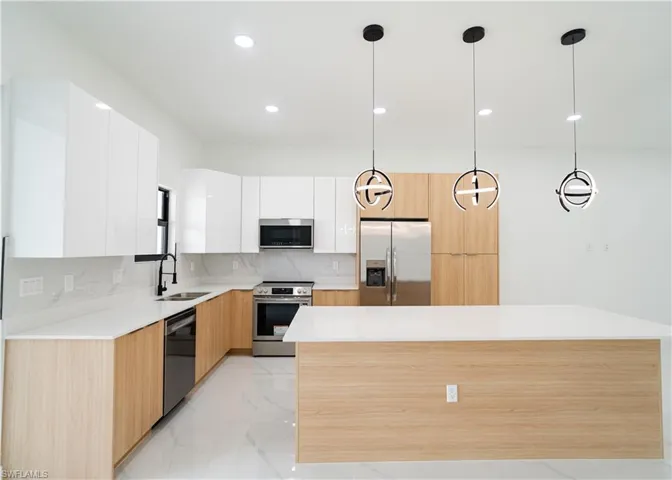 Kitchen featuring modern cabinets, hanging light fixtures, appliances with stainless steel finishes, and recessed lighting