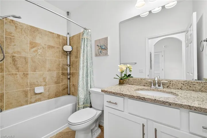 Full bathroom featuring shower / tub combo with curtain, vanity, and light tile patterned flooring