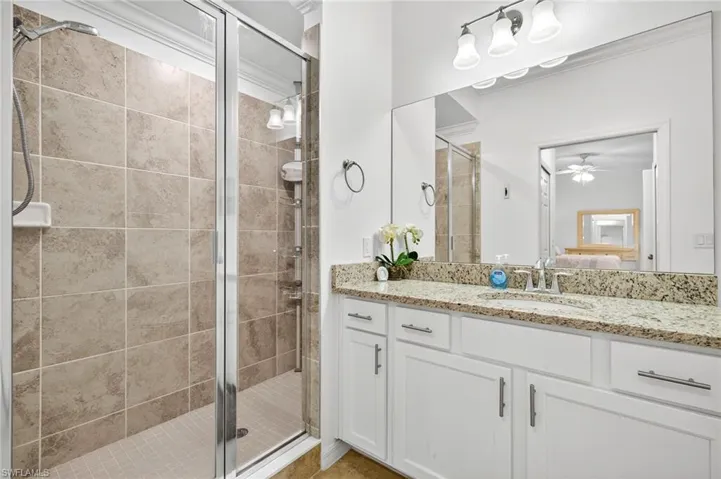 Ensuite bathroom with vanity, a shower stall, and a ceiling fan